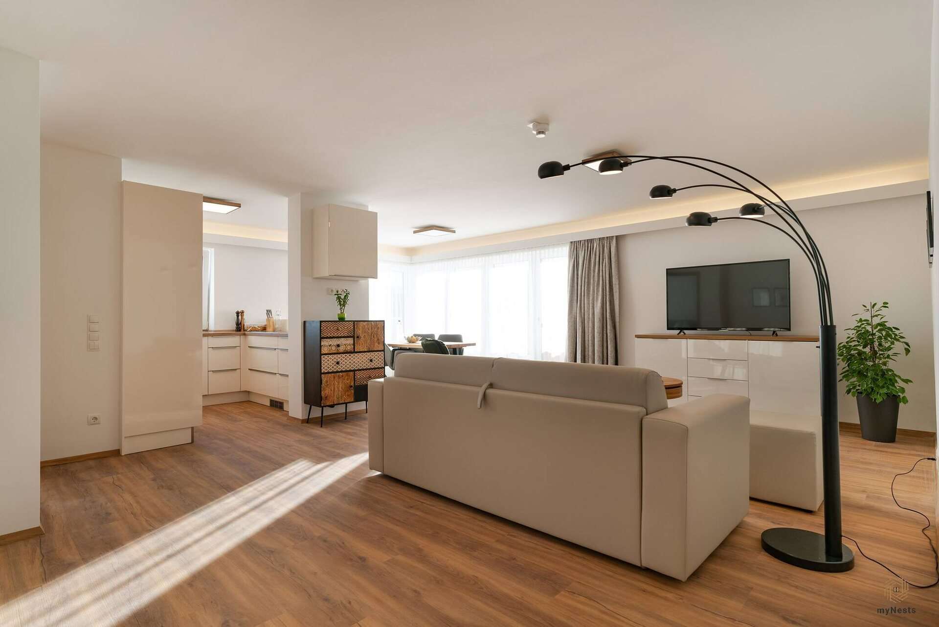 Obývací část s pohovkou, televizí a obloukovou lampou v apartmánu Bachstelze 10