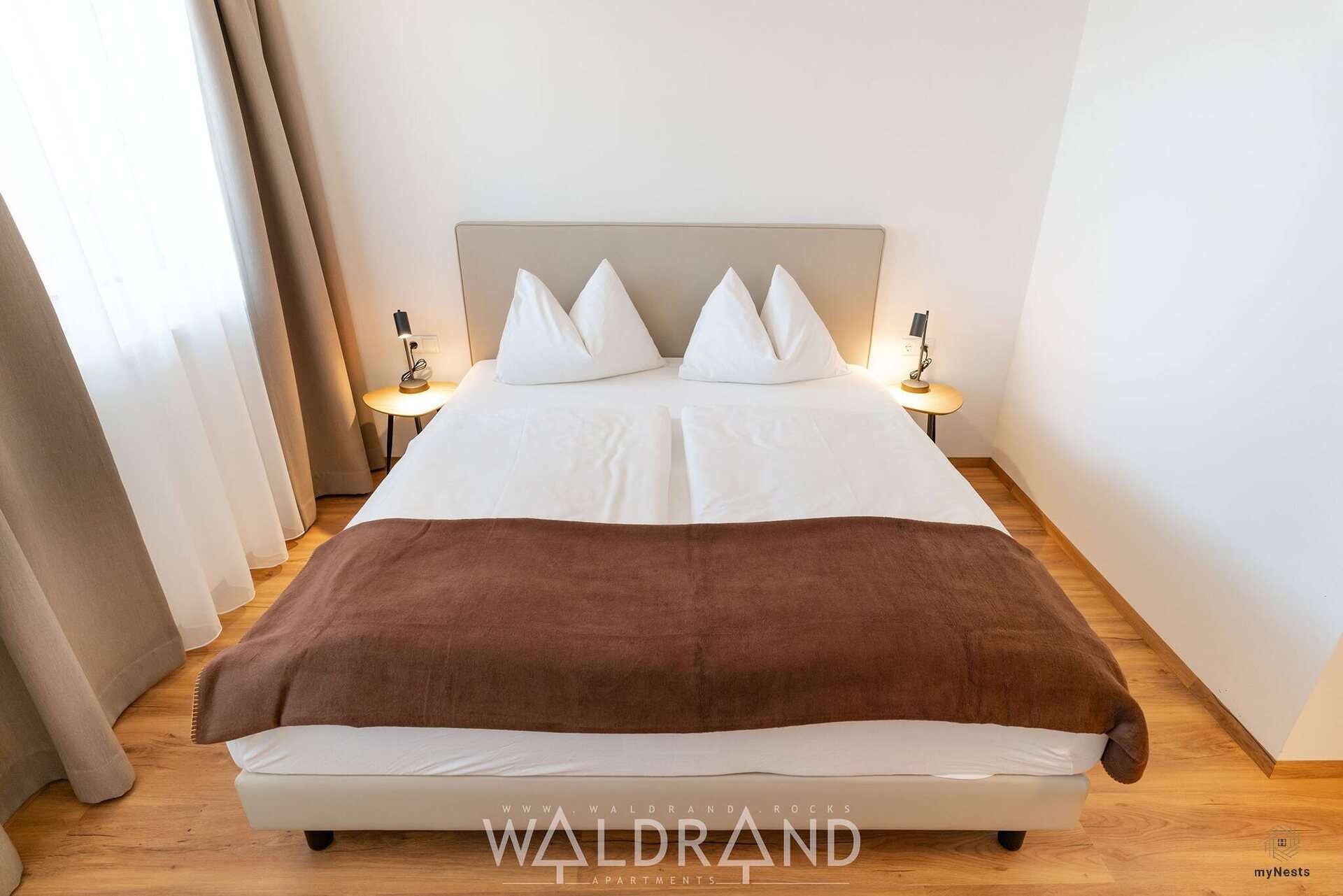 Ložnice s manželskou postelí a hnědou přikrývkou v apartmánu Buntspecht 1