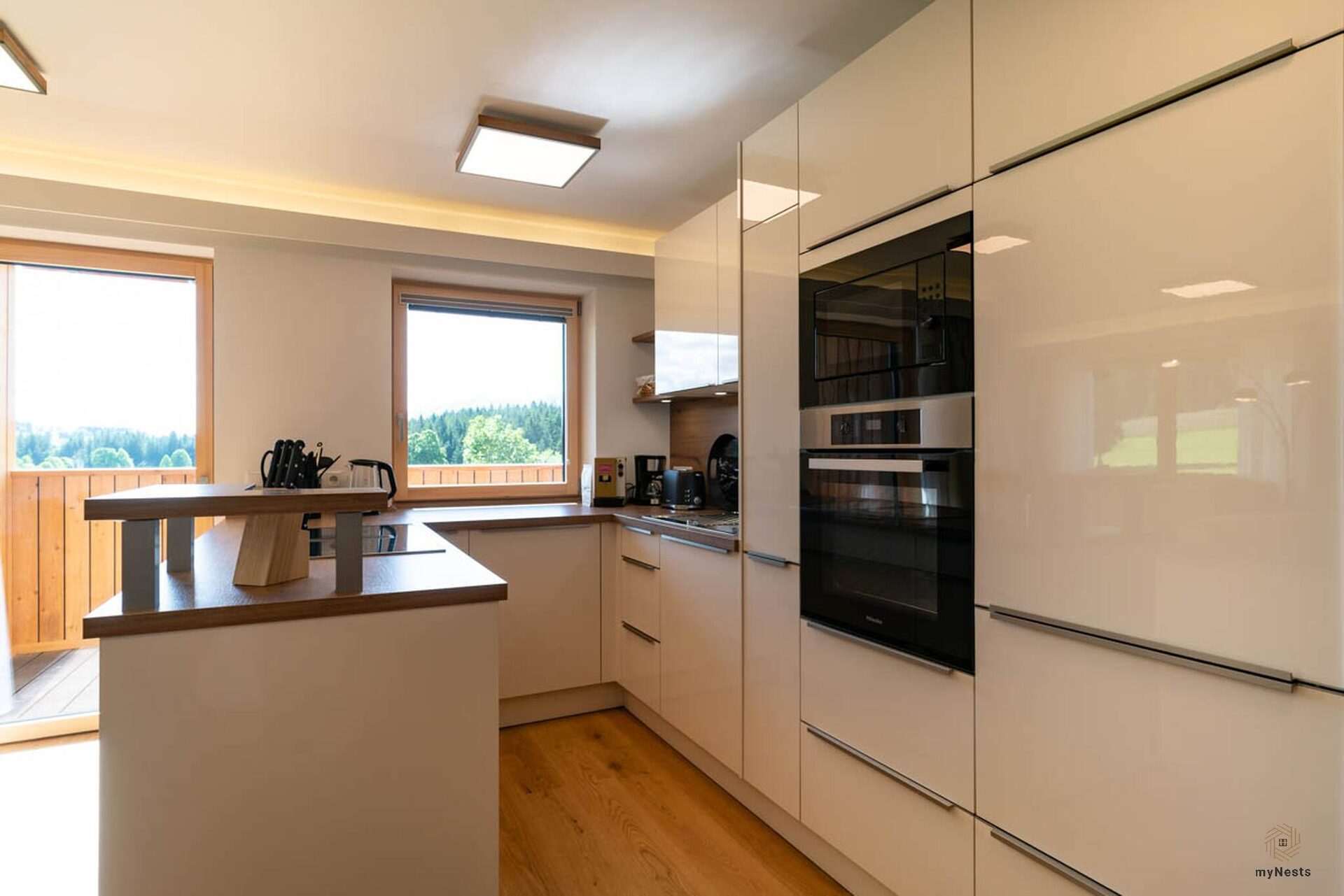 Bílá kuchyň s vestavnými spotřebiči a okny na terasu v apartmánu Fink 6