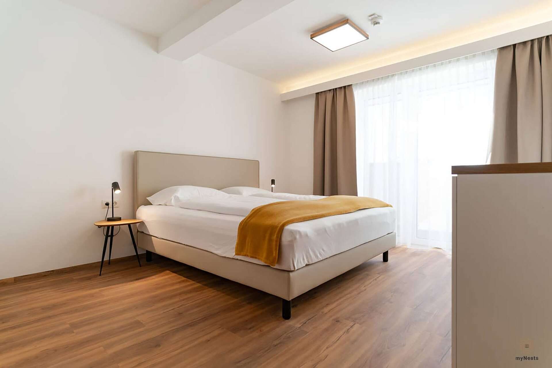 Ložnice s manželskou postelí a nočním stolkem v apartmánu Rotschwänzchen 12