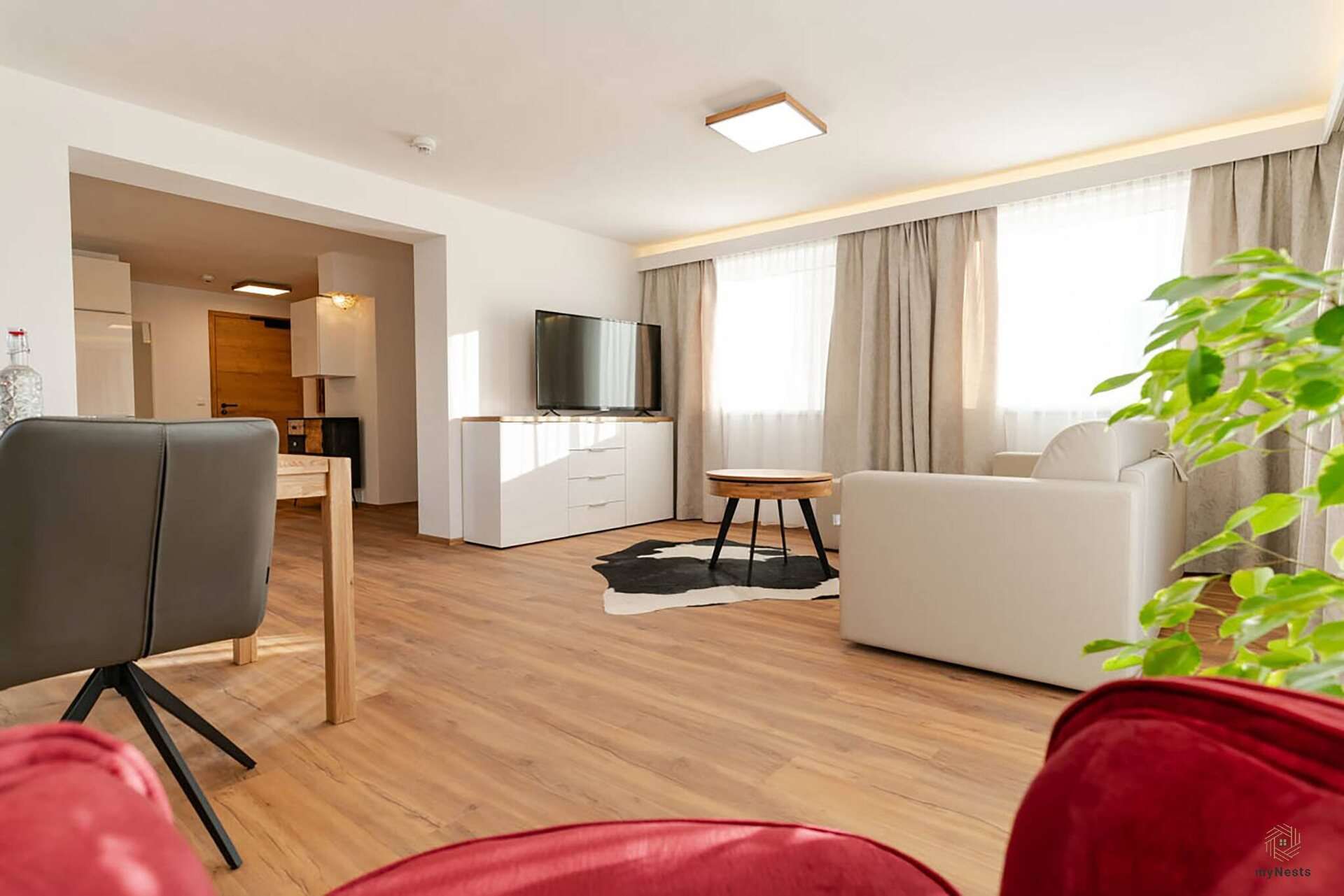 Obývací část s křeslem, televizí a výhledem do kuchyně v apartmánu Rotschwänzchen 12