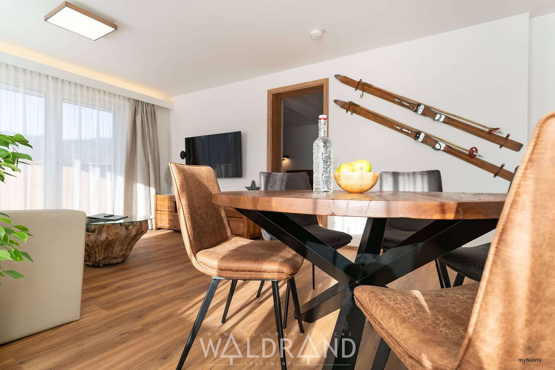Jídelní stůl s koženými židlemi a starými dřevěnými lyžemi na stěně v apartmánu Schnepfe 11