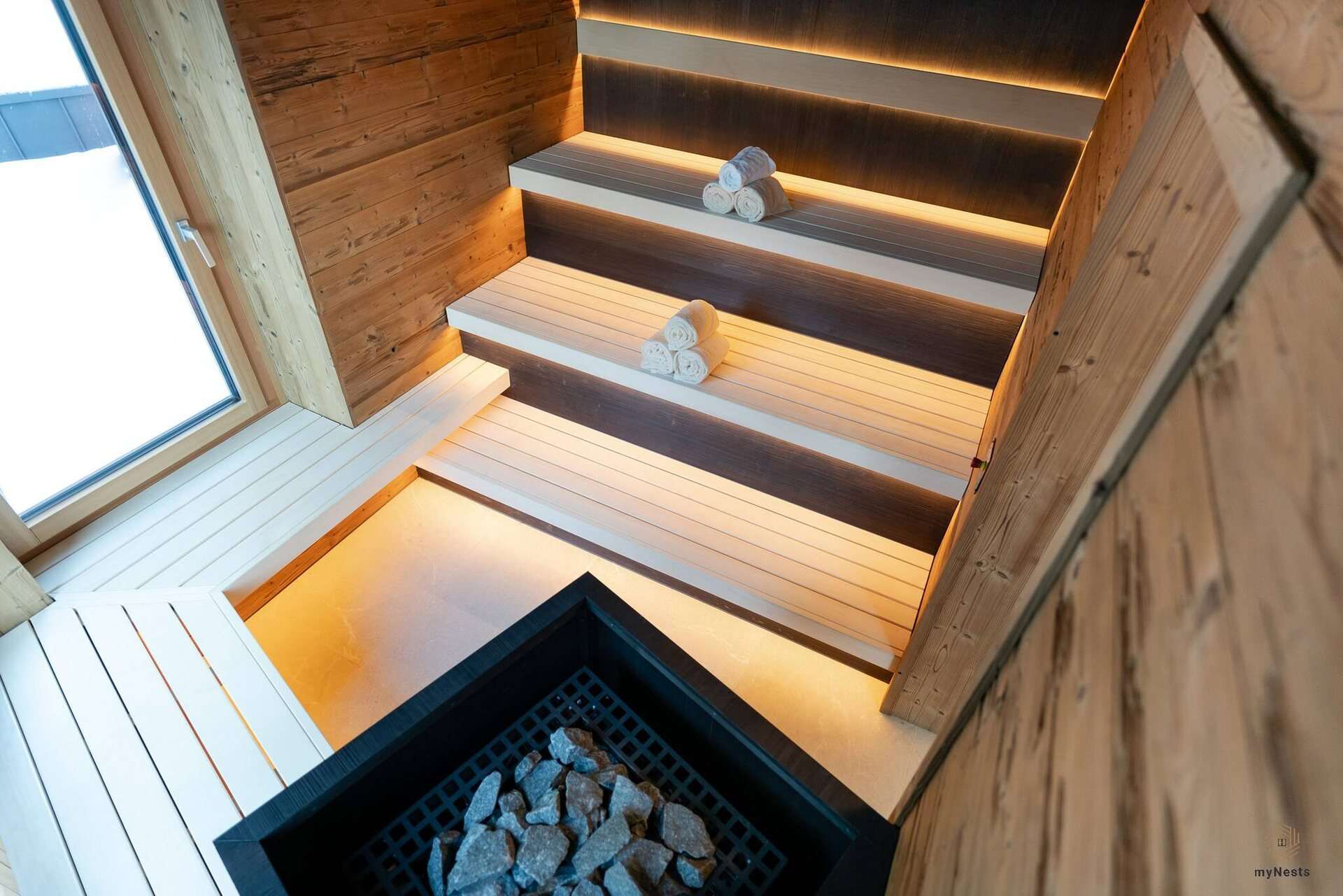 Finská sauna s dřevěnými lavicemi, ručníky a saunovými kamny